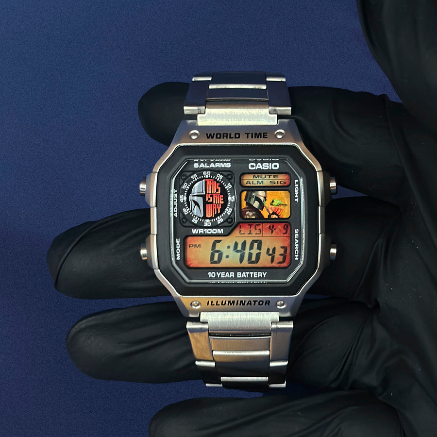 Casio AE-1200 Beskar Protocol en acier en main, cadran au casque métallique sur fond orange, de K-Project Lab