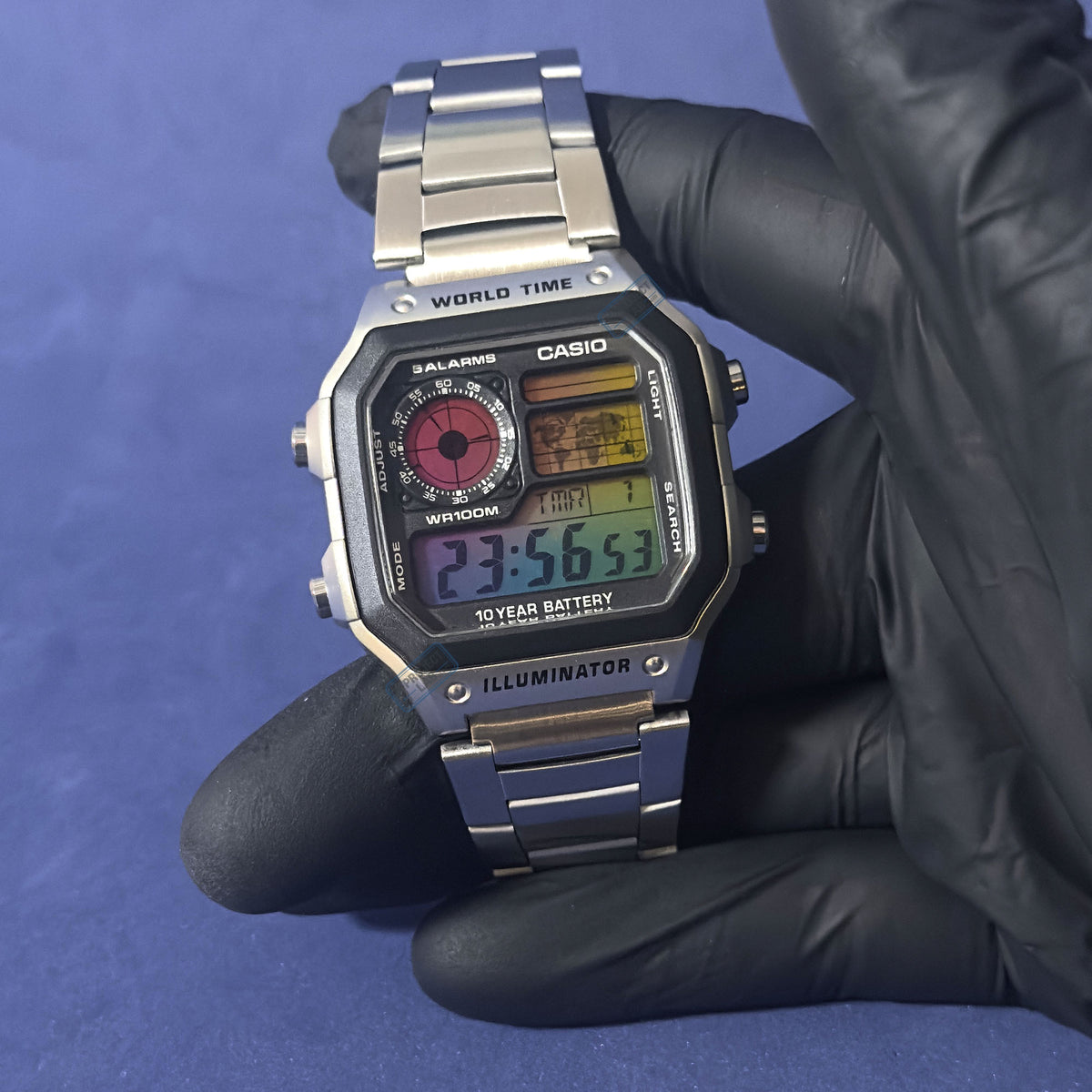 Casio AE-1200 Chromatic Grid teräksisenä mustassa hansikkaassa, punainen kellotaulu ja väridigitit, K-Project Labilta