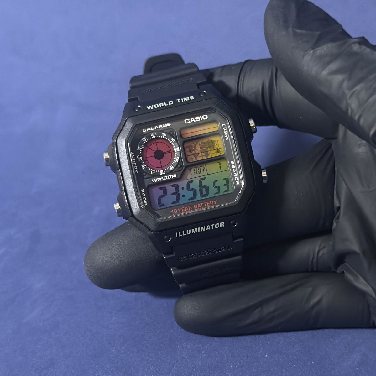 K-Project Labin Casio AE-1200 Chromatic Grid mustana hartsina, hansikkaassa kädessä, sateenkaarinäyttö valaistuna