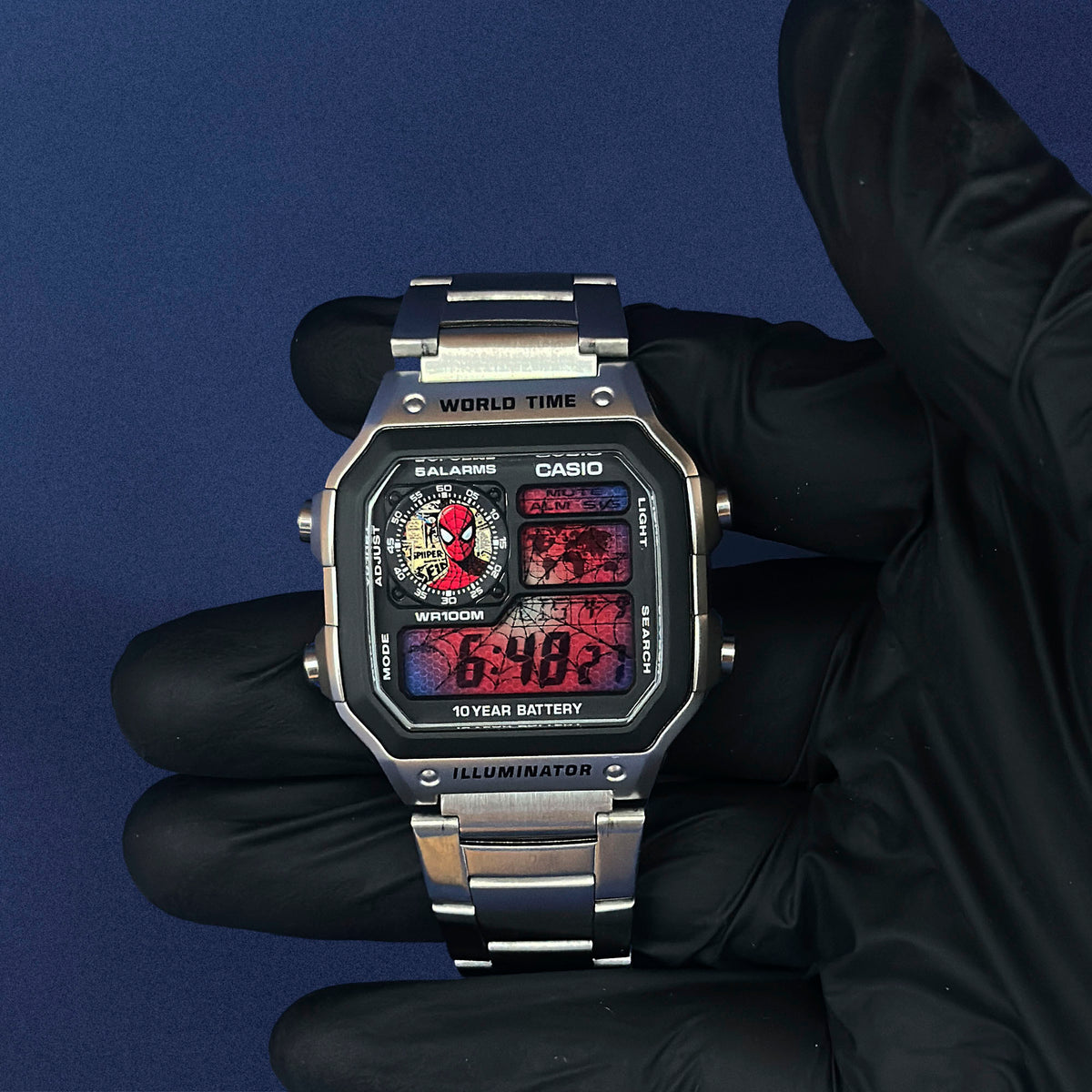 Casio AE-1200 Comic Verse Web Archive in Stahl, mit schwarzem Handschuh vor blauem Grund, von K-Project Lab
