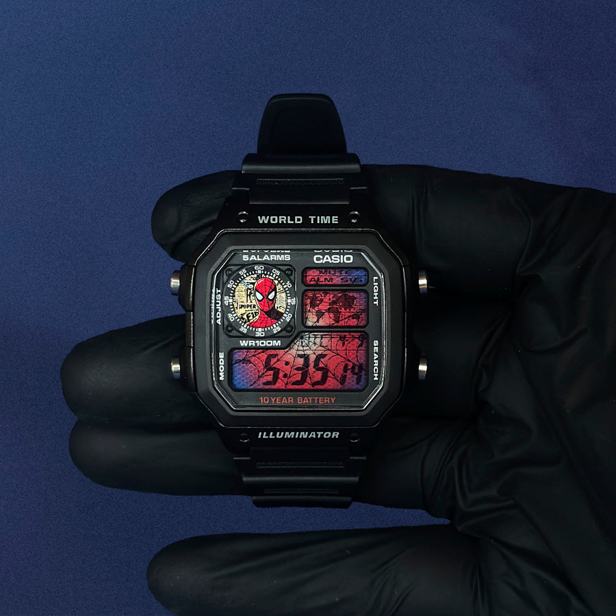 Casio AE-1200 Comic Verse Web Archive en résine noire tenue en main, cadran rouge et bleu, de K-Project Lab