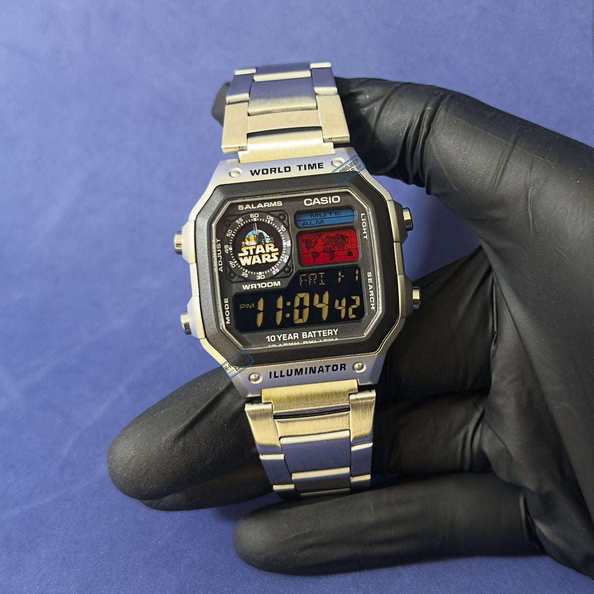Casio AE-1200 Imperial Wars teräksisenä mustassa hansikkaassa sinistä taustaa vasten, K-Project Labilta