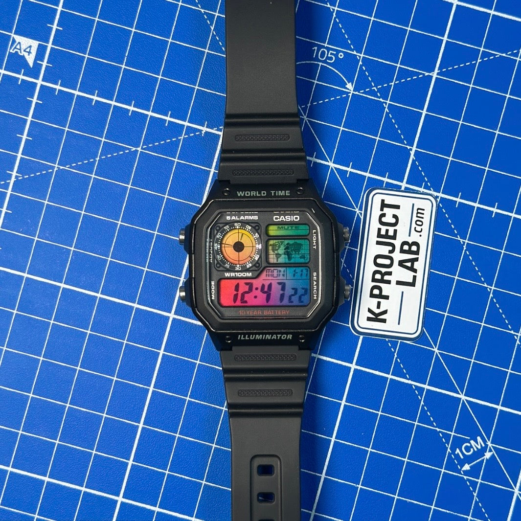 Casio AE-1200 Amber Signal in schwarzem Resin, mit ausgestrecktem Armband auf blauer Oberfläche, von K-Project Lab