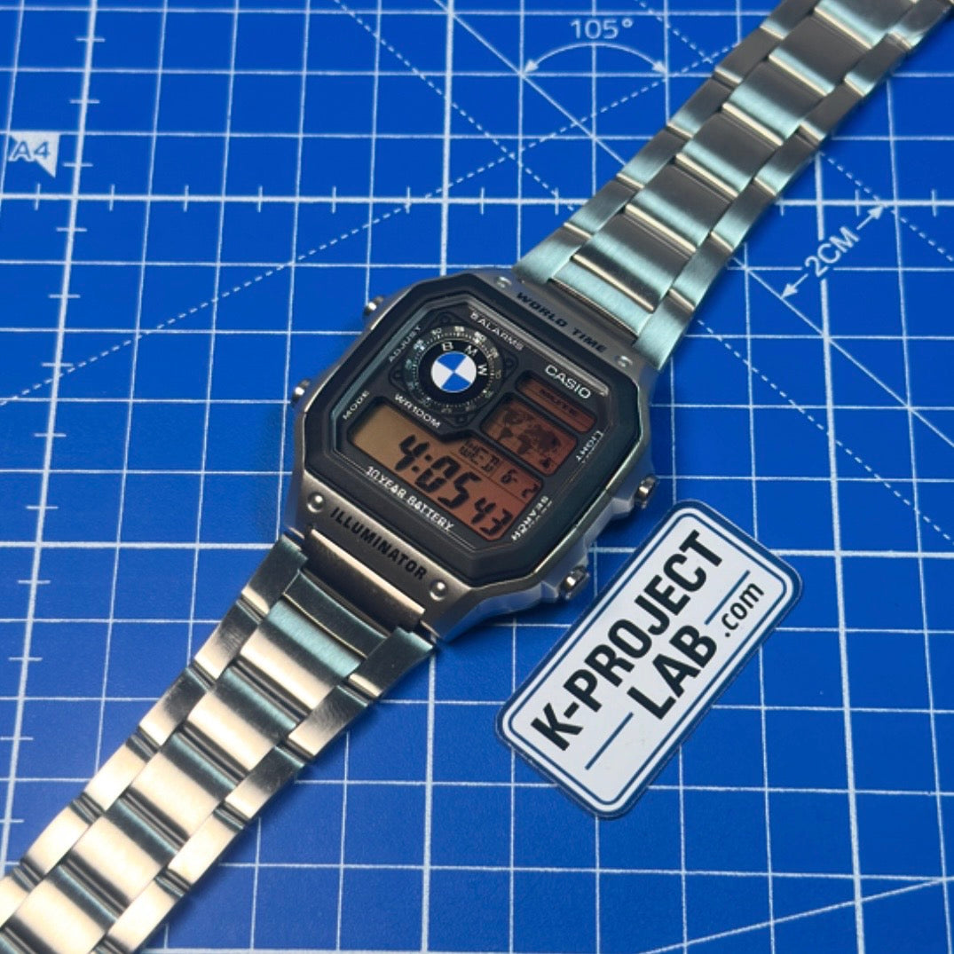 K-Project Labin muokkaama Casio AE-1200 Midnight Bavarian teräksisenä, ranneke levitettynä siniselle alustalle