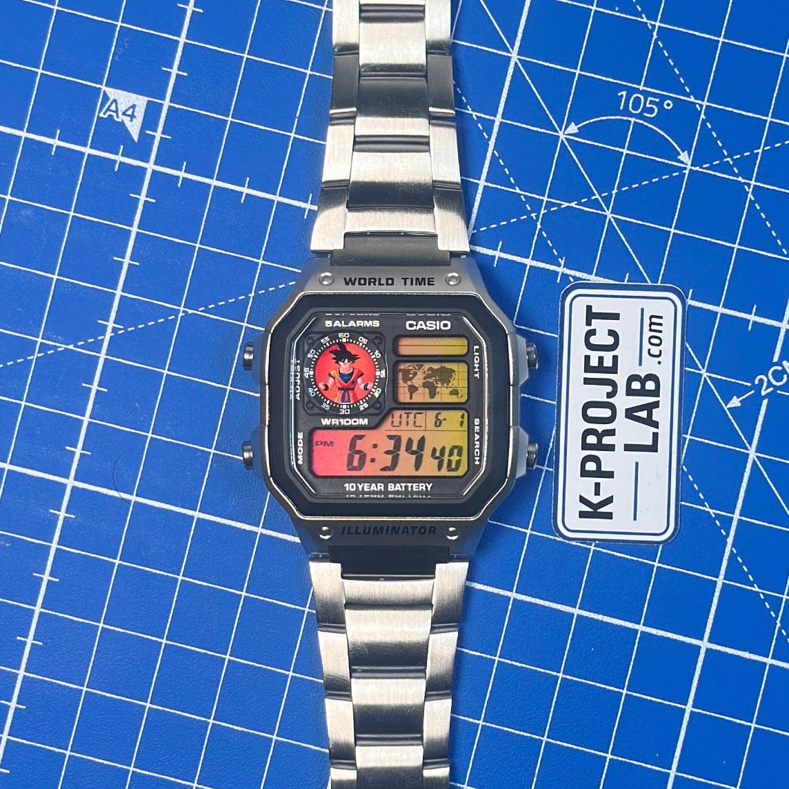 Casio AE-1200 Saiyan Signal in Stahl, von vorn auf blauer Oberfläche, Display in Rot und Gelb, von K-Project Lab