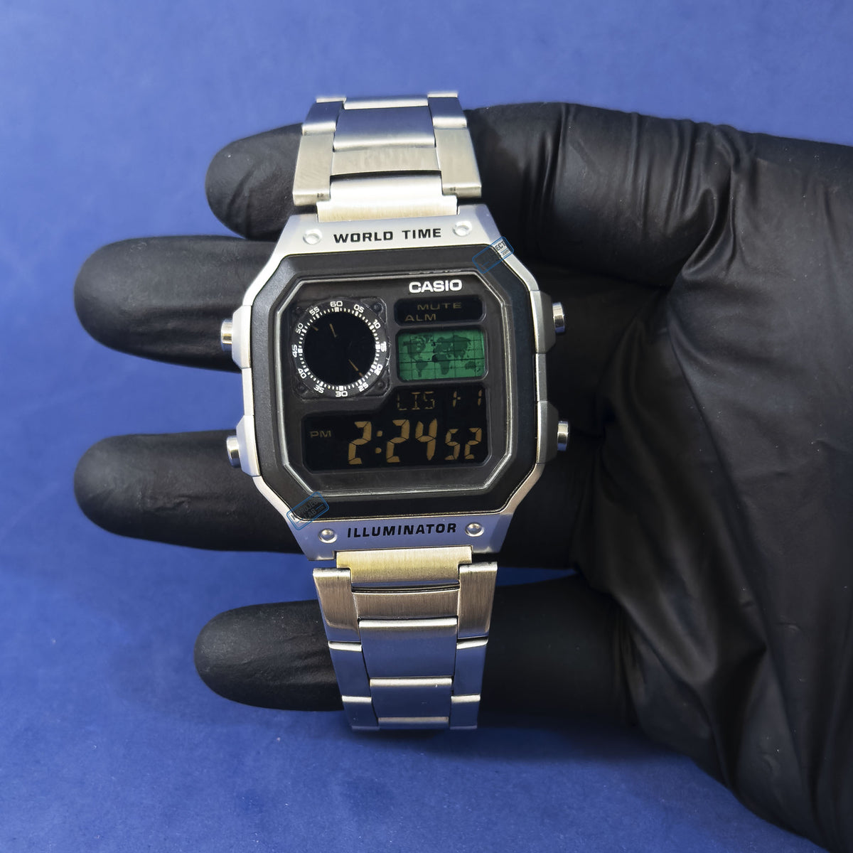 Casio AE-1200 Obsidian Grid teräksisenä mustassa hansikkaassa, musta kellotaulu ja meripihkadigitit, K-Project Labilta