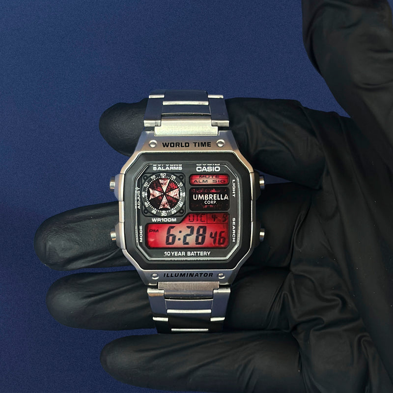 Casio AE-1200 Outbreak Protocol i stål holdt med sort handske, rødt display, fra K-Project Lab