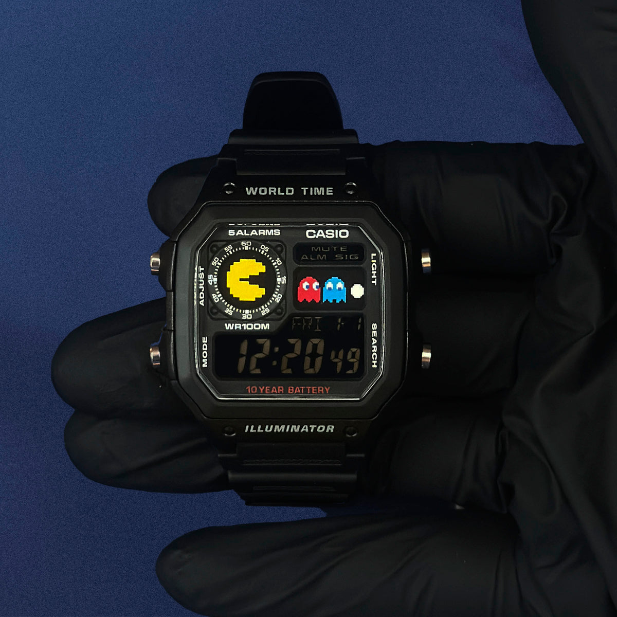 K-Project Labin Casio AE-1200 Pixel Chase mustana hartsina, hansikkaassa kädessä sinisellä taustalla