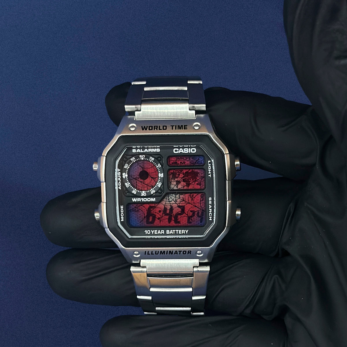 Casio AE-1200 Spider Sense Web Protocol i stål hållen i handske, röd display, från K-Project Lab