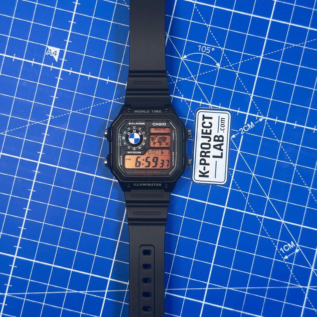 Casio AE-1200 Midnight Bavarian mustana hartsina sinisellä alustalla, meripihkanäyttö, K-Project Labilta
