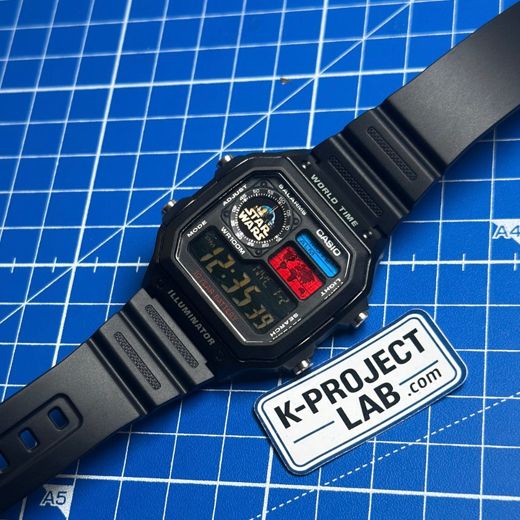 Casio AE-1200 Imperial Wars mustana hartsina viistosti sinisellä matolla, K-Project Labilta